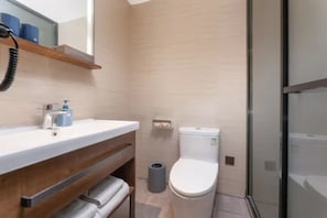 A modern bathroom with a wooden vanity, a toilet, and a glass shower enclosure.