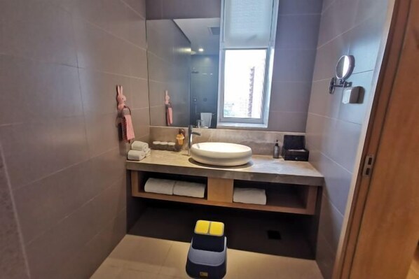 Une salle de bain moderne avec un grand miroir, un lavabo et une fenêtre.