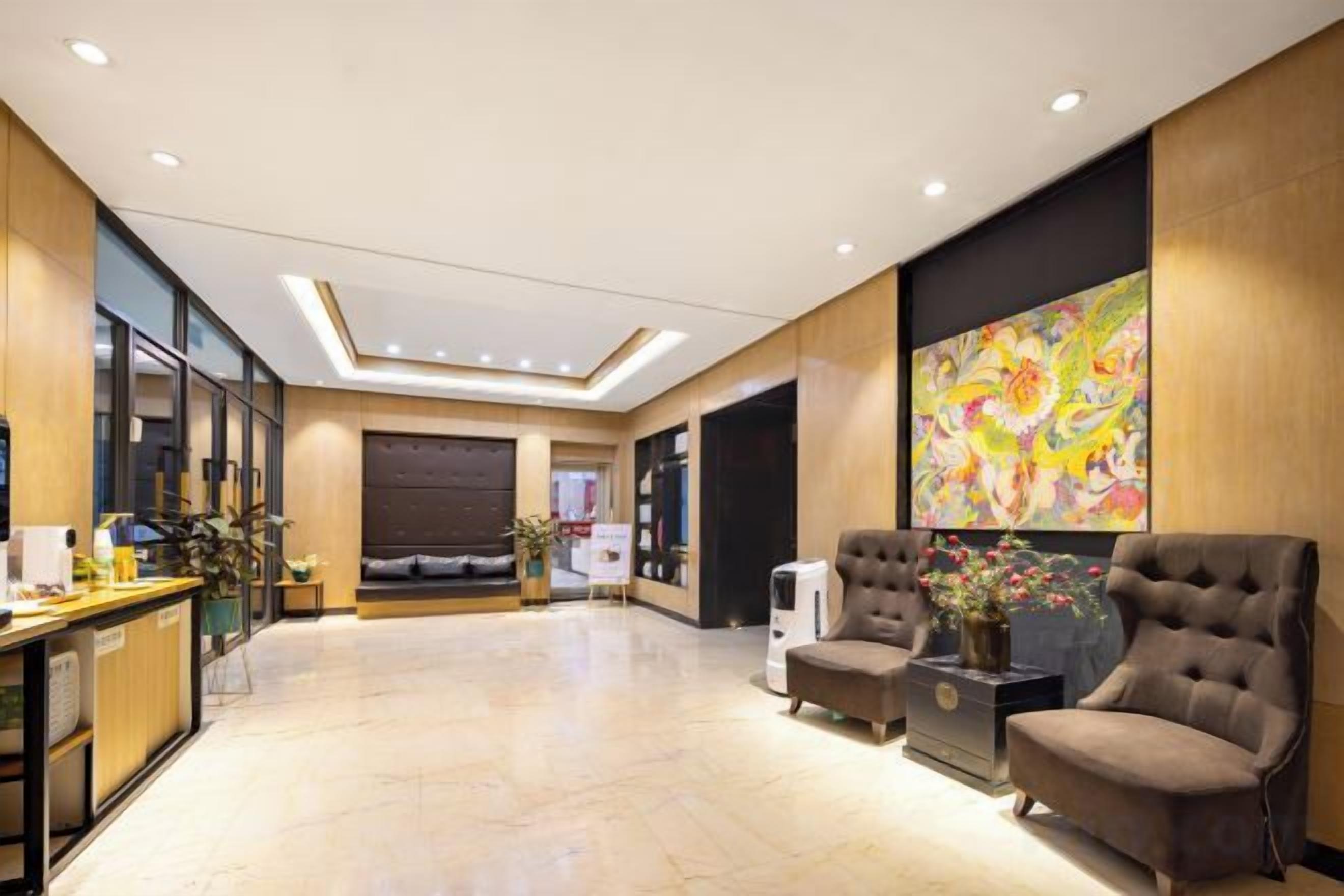 A hotel lobby with a reception desk, seating area, and a large abstract painting.