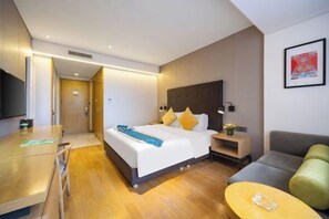 Une chambre d’hôtel moderne équipée d’un lit, d’un canapé, d’une petite table et d’un téléviseur.