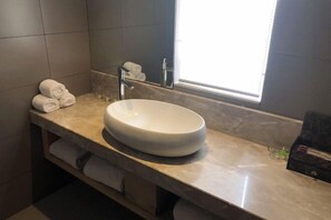 Une salle de bain avec un grand lavabo blanc, un porte-serviettes et une fenêtre.