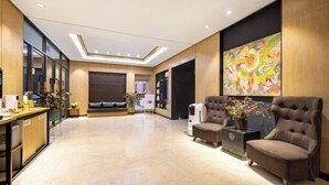 A spacious lobby with a reception desk, seating area, and a large abstract painting on the wall.