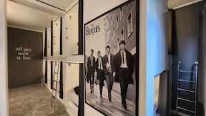En hall med en Beatles-affisch, numrerade dörrar och en stege.