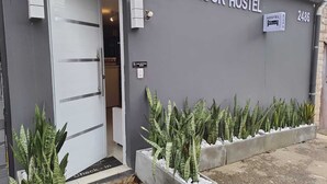 Vila Rock Hostels exteriör med en dörr, skyltar och planteringslådor med gröna växter.