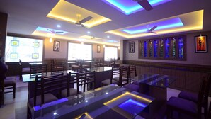 A restaurant with glass tables and chairs, ceiling fans, and recessed lighting. - North Centre (Kanayannur)