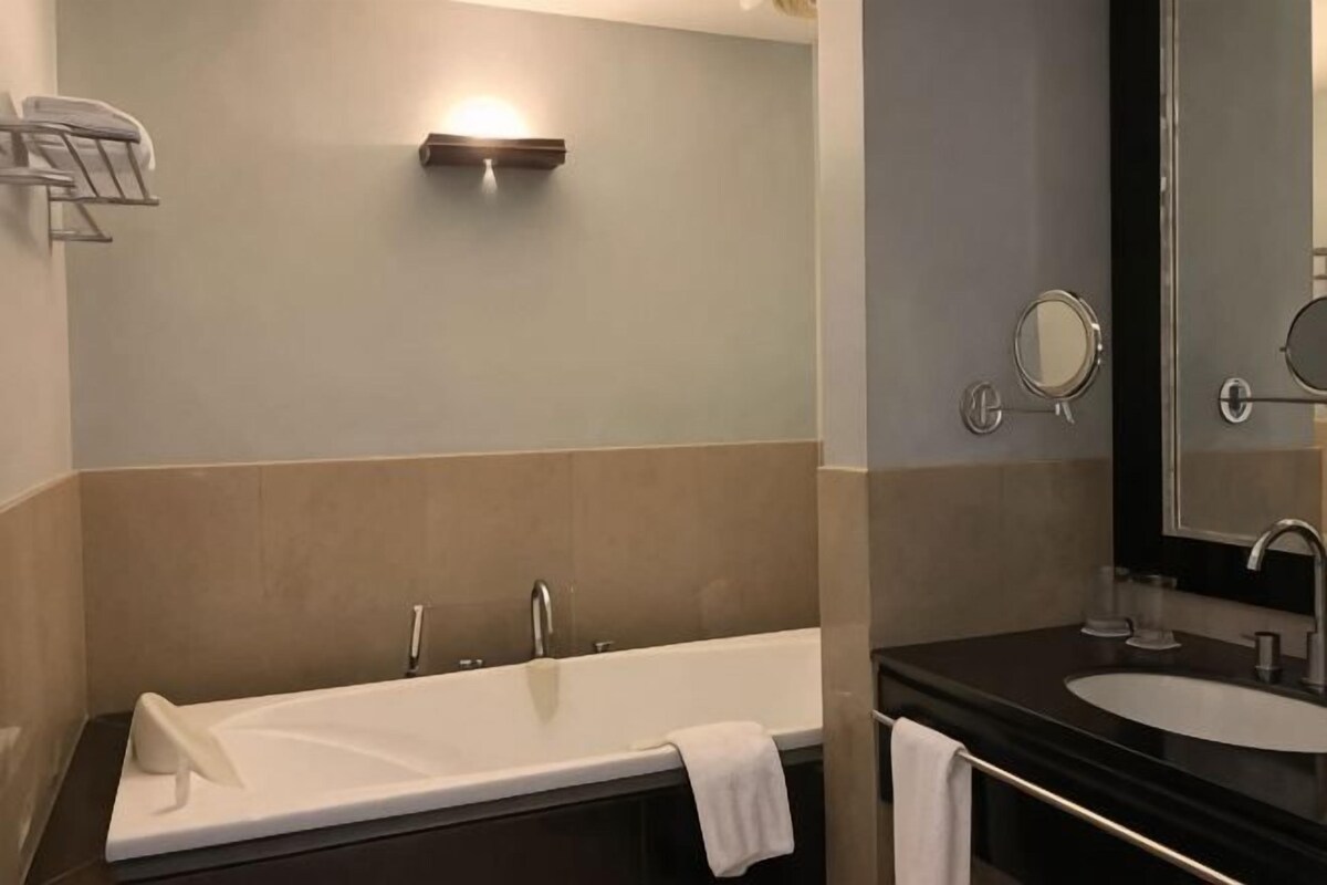 Un bagno con una vasca, un lavandino e uno specchio.