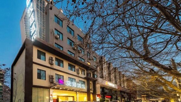 Hotel de varios pisos con un restaurante visible en la planta baja, rodeado de árboles.