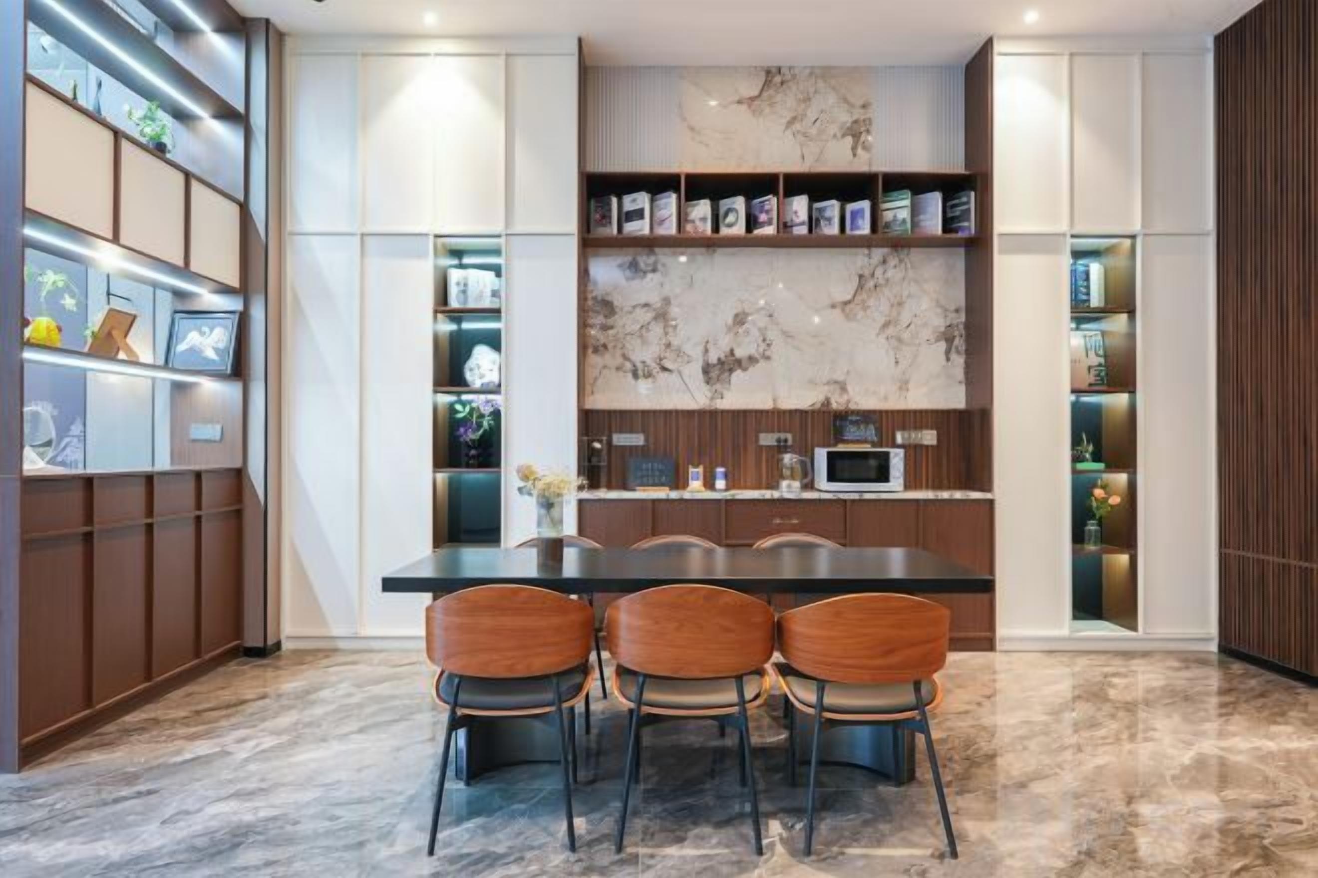A modern kitchen with a marble backsplash, built-in shelves, and a dining area with chairs.