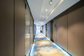 Un pasillo largo y estrecho con piso y paredes reflectantes, que lleva a una salida distante.