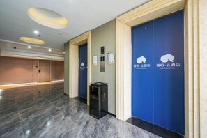 En hotellobby med ett marmorgolv, blå dörrar och en papperskorg.