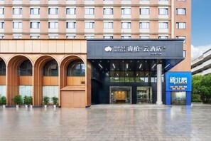 A hotel entrance with a modern facade, large windows, and a clear sky. - RIPPLE Hotel(Minhou Fuzhou University City Yongjia Tiandi Square Branch) (Fuzhou)
