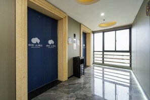 A hallway with a blue door, a trash bin, and a window with a view. - RIPPLE Hotel(Minhou Fuzhou University City Yongjia Tiandi Square Branch) (Fuzhou)