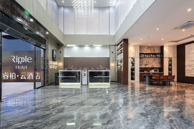 A hotel lobby with a reception desk, a seating area, and a bar.