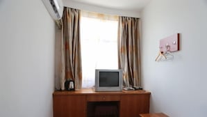A room with a wooden desk, a television, a small table, and a wall-mounted coat rack. - Shanghai Baixing Hotel (Shanghai)