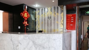 A reception area with a marble counter, a decorative red sign, and a vertical panel with yellow accents. - Shanghai Baixing Hotel (Shanghai)