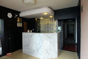 A reception desk with a marble top, a clock, and a sign on the wall. - Shanghai Baixing Hotel (Shanghai)