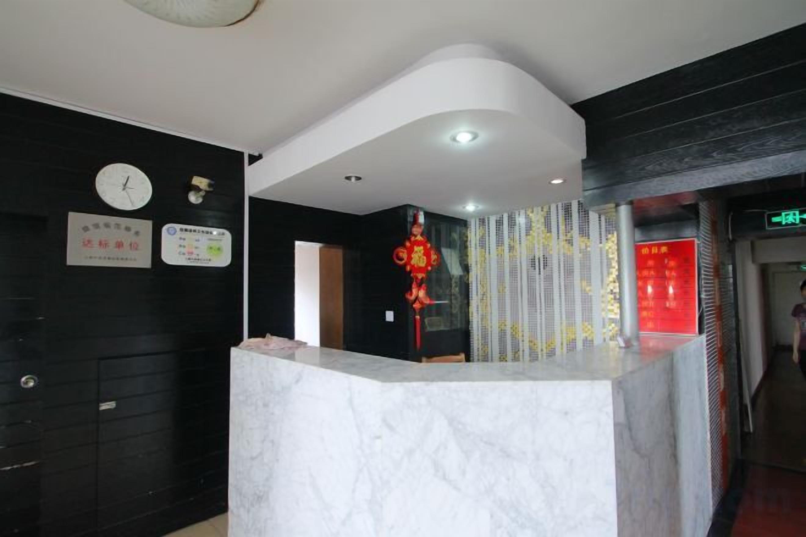 A hotel reception area with a marble counter, black walls, and a clock.