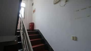 A staircase with a handrail, a red fire extinguisher, and a wall-mounted electrical outlet.