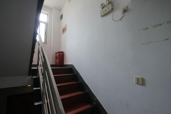 A staircase with a handrail, a red fire extinguisher, and a wall-mounted electrical outlet.