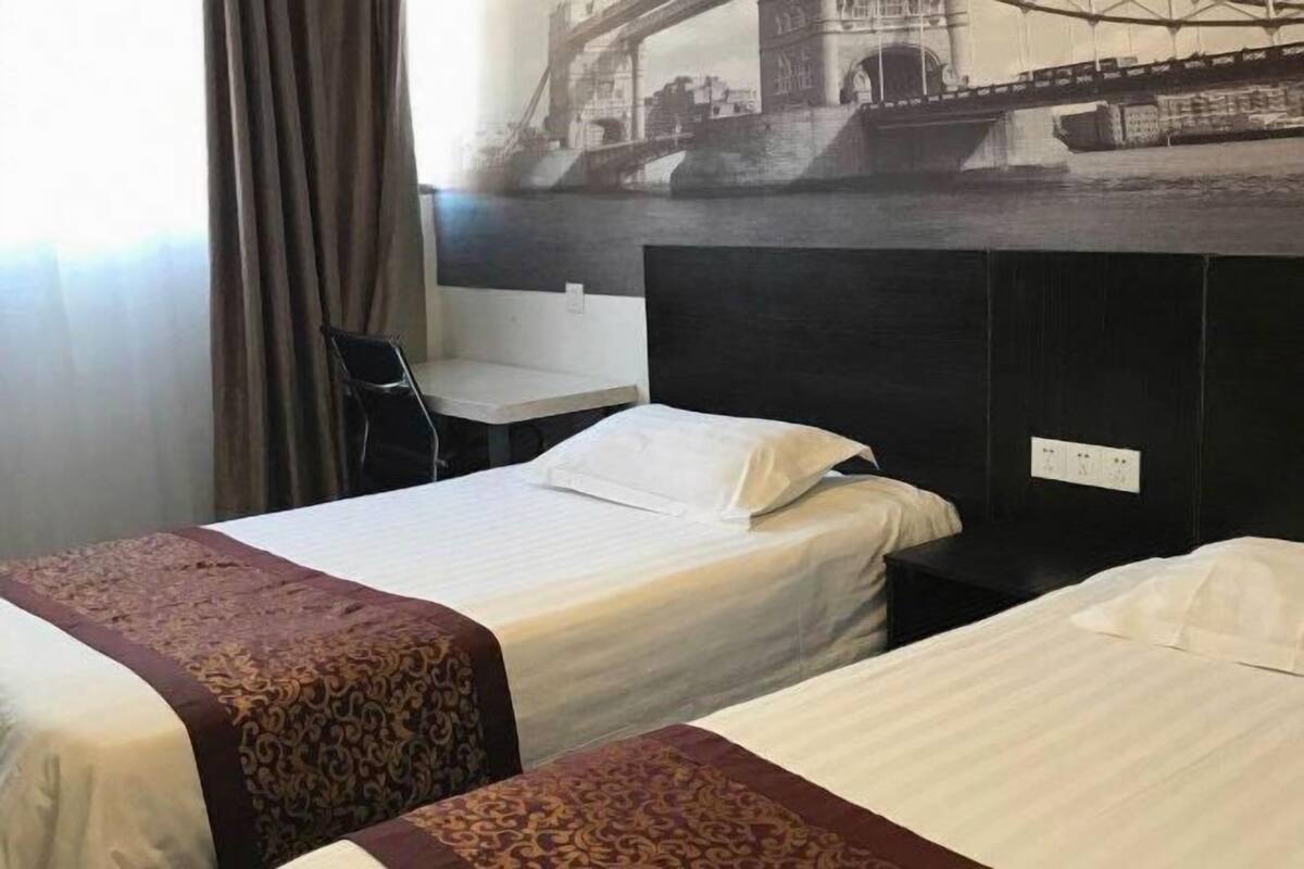 A hotel room with two beds, a desk, and a view of a bridge.