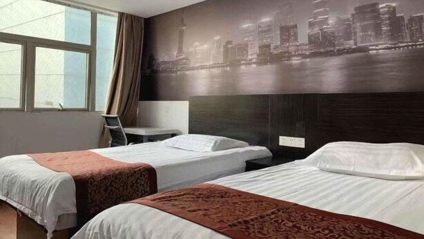 A hotel room with two beds, a cityscape mural, a desk, and a window. - Shanghai Baixing Hotel (Shanghai)