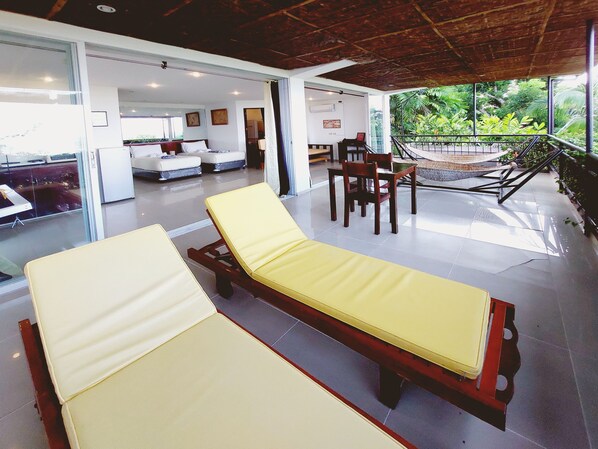 A modern hotel room with a glass wall, a wooden ceiling, and a balcony with a hammock. - Bohol Vantage Resort (Dauis)