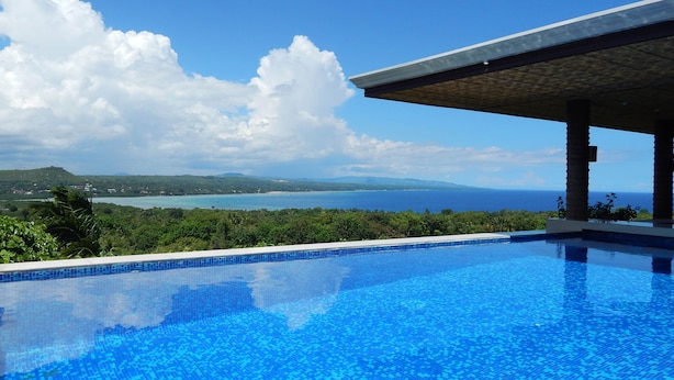 A clear blue pool with a view of the ocean and hills. - Bohol Vantage Resort (Dauis)