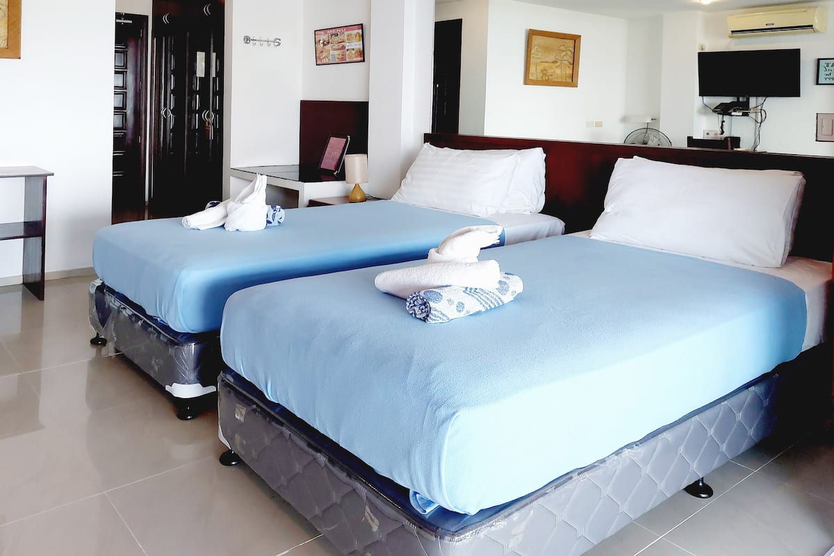 A hotel room with two beds, a desk, a chair, a TV, and a mirror.