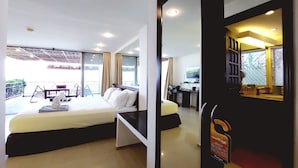 A hotel room with a bed, a desk, and a balcony. - Bohol Vantage Resort (Dauis)