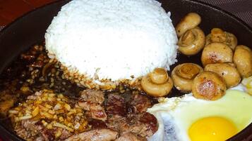 Uma refeição com arroz, cogumelos, carne e um ovo.
