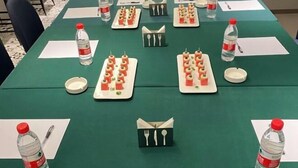 A conference table set with water bottles, plates of food, and napkin holders. - Home Inn Business Hotel (Zhengzhou 460 Hospital Bishagang Metro Station Branch) (ZHENGZHOU)