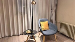 A modern room with a blue chair, a small table with a cup and saucer, a floor lamp, and a radiator. - Home Inn Business Hotel (Zhengzhou 460 Hospital Bishagang Metro Station Branch) (ZHENGZHOU)