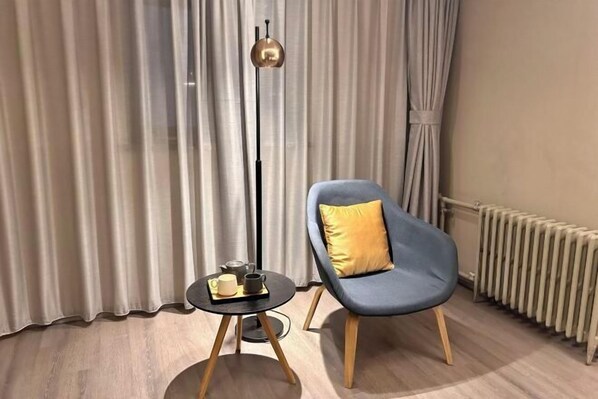 A modern room with a blue chair, a small table with a cup and saucer, a floor lamp, and a radiator. - Home Inn Business Hotel (Zhengzhou 460 Hospital Bishagang Metro Station Branch) (ZHENGZHOU)