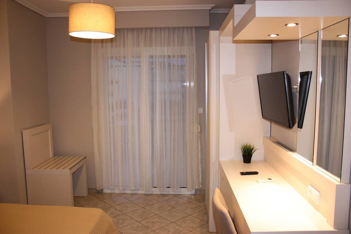 A modern bathroom with a white sink, mirror, and a television mounted above it.