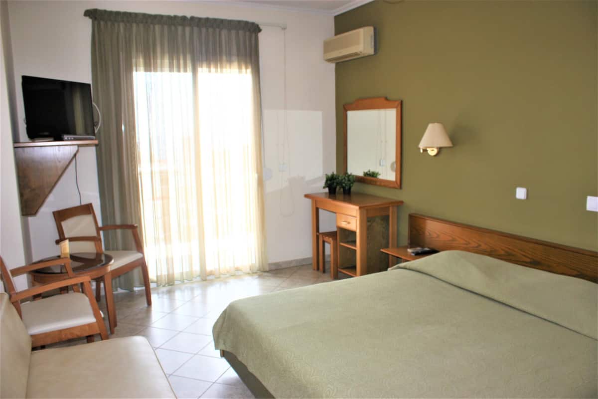 A hotel room with a bed, a desk, a chair, a television, and a window with curtains.