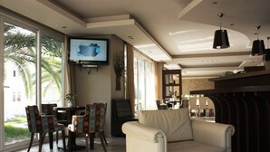 A living room with a sofa, chairs, a TV, and a dining area with a table and chairs. - Hotel Cariatis (Nea Propontida)
