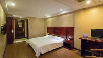 A hotel room with a bed, a desk with a computer, and a television.