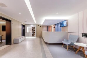 A modern reception area with a reception desk, seating area, and a television screen. - Homeinn Hotel ( Ningbo K11 Shopping Center, Jiangxia Bridge Metro Station Branch） (Ningbo)