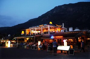 A restaurant with outdoor seating and a mountain backdrop. - Belcekiz Beach Club - All Inclusive (Fethiye)