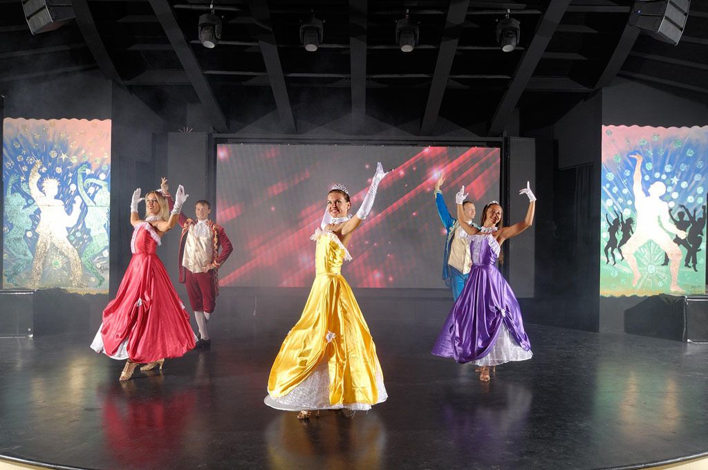 Um palco com artistas em trajes coloridos.