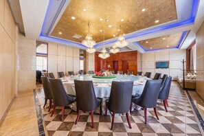 A conference room with a round table, chairs, and a chandelier. - Huadong Hotel (Qitaihe (Xinjiang))