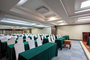 Un salón de conferencias con filas de mesas y sillas, un banco de madera y un suelo a cuadros.