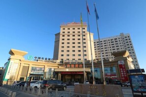Un hotel con una entrada destacada, varios pisos y un asta con bandera.