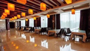A spacious dining area with tables and chairs, wooden beams on the ceiling, and large windows with curtains. - Huadong Hotel (Qitaihe (Xinjiang))