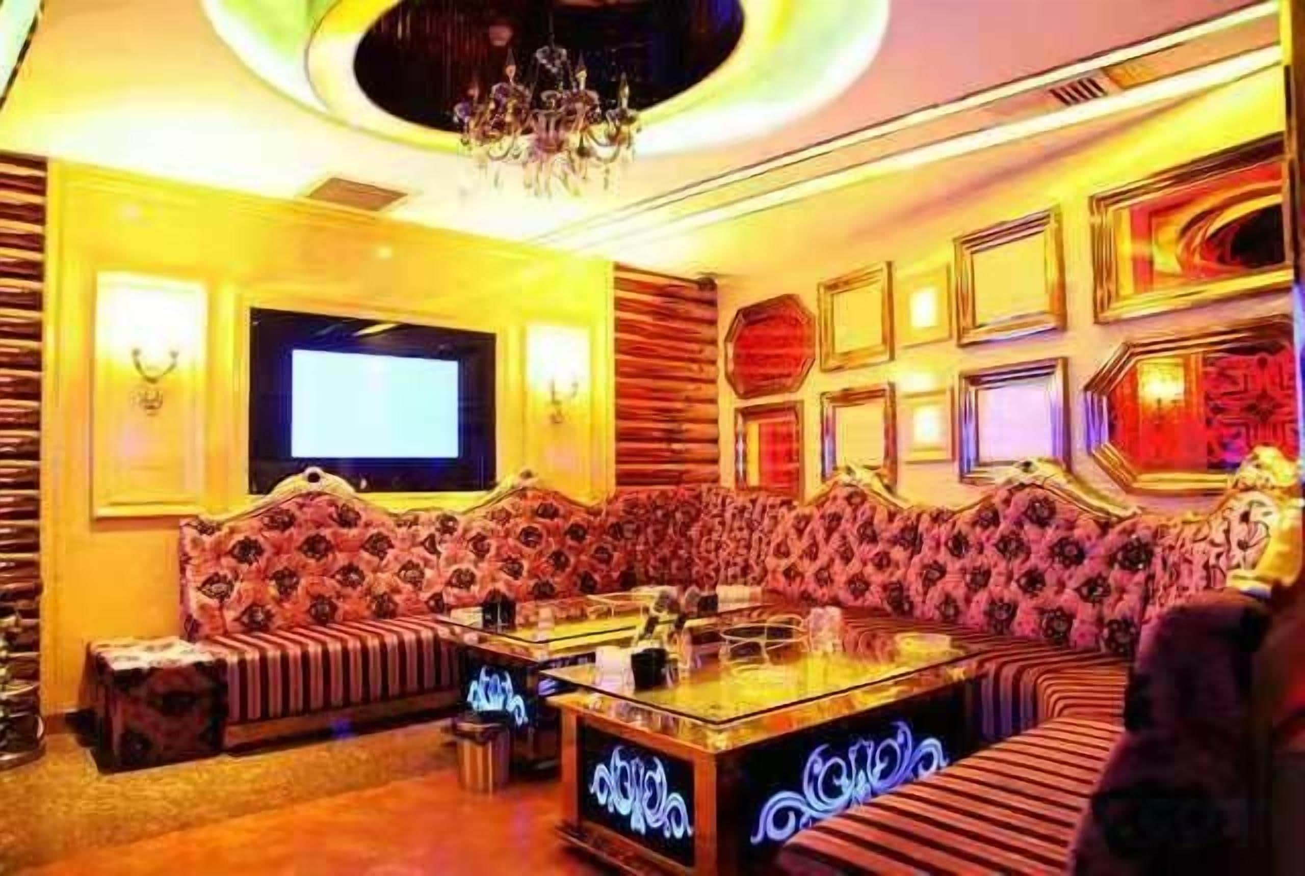 A room with a large sofa set, a television, and a chandelier.