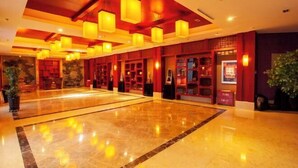A spacious lobby with a polished marble floor, red wooden paneling, and multiple hanging lantern-style lights. - Huadong Hotel (Qitaihe (Xinjiang))