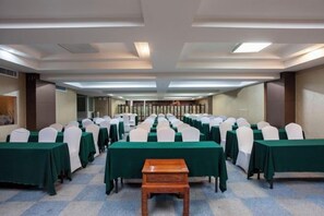 Un salón de conferencias con filas de mesas y sillas, un banco de madera y piso alfombrado.