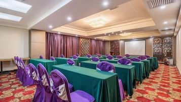 A conference room with tables and chairs, a carpeted floor, and a projector screen.