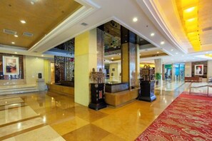 A hotel lobby with a reception desk, a red carpet, and a staircase leading to an upper level. - Huadong Hotel (Qitaihe (Xinjiang))