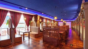 Un restaurante con techo estrellado, mobiliario de madera y cortinas rojas.